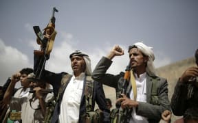 Houthi rebel fighters hold their weapons and shout slogans during a gathering aimed at mobilizing more fighters before heading to battlefronts.
