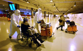 Workers wearing protective masks and suits help Chinese travellers leaving the arrival hall of Rome–Fiumicino International Airport, near Rome, on December 29, 2022 after being tested for the Covid-19 coronavirus.