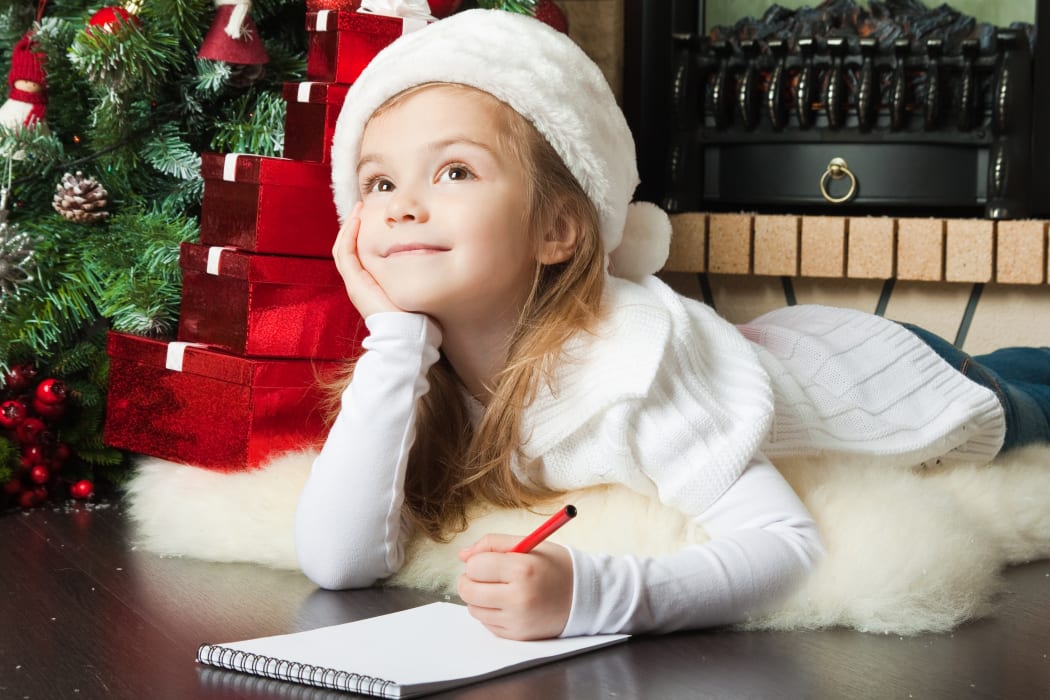 Girl in Santa hat writing letter for Christmas.