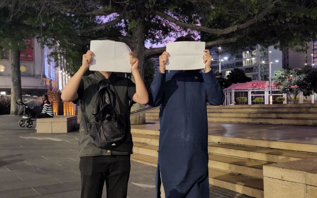 Protestors in Aotea Square hold white A4 paper as a symbol of defiance against censorship by the Chinese government.