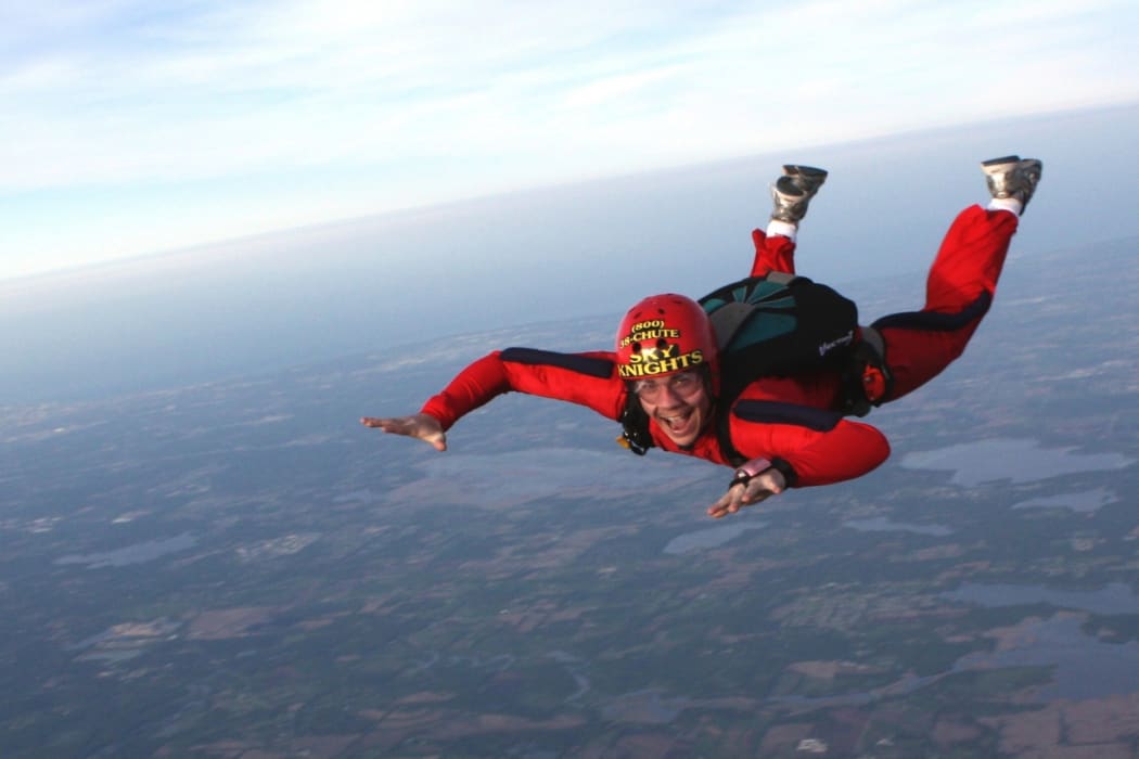 a man sky diving in a red suit and helmet