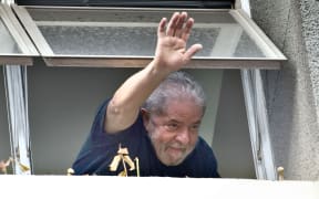 Former Brazilian President Luiz Inacio Lula da Silva waves at supporters from a window of the Workers Party state headquarters in Sao Paulo, on March 4, 2016