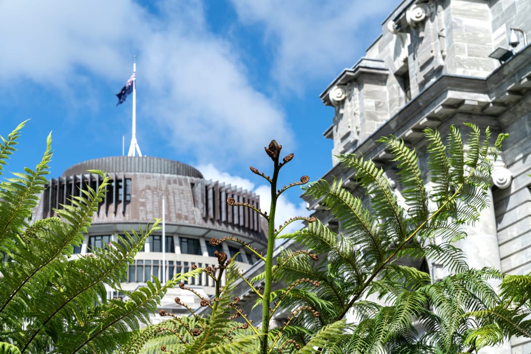 New Zealand Government buildings, House neo classical style House of Parliament with Beehive behind with iconic ponga fern frond one of NZ's emblems.