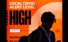 A government public information notice reminding people of 'High' (or 'Tier 2') coronavirus restrictions lights up the advertising panel of a bus stop on Knightsbridge in London, England/