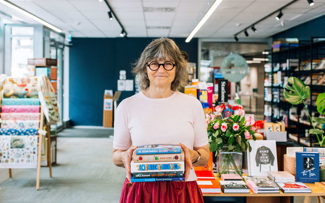 New Zealand's Best Emerging Bookseller Lisa Adler holds a selection of books in a boook store