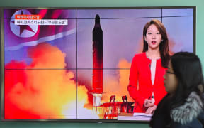 A woman walks past a television screen showing file footage of North Korea's missile launch at a railway station in Seoul on February 12, 2017.