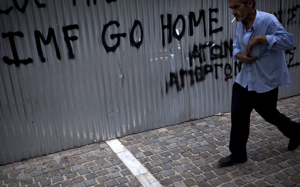 A man walks in front of a graffiti reading ''IMF go home'' in Athens.