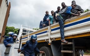 Zimbabwean anti-riot police forces watch men, arrested during violent protests triggered by a sudden rise in fuel prices announced by Zimbabwean President, for their hearing in Harare,