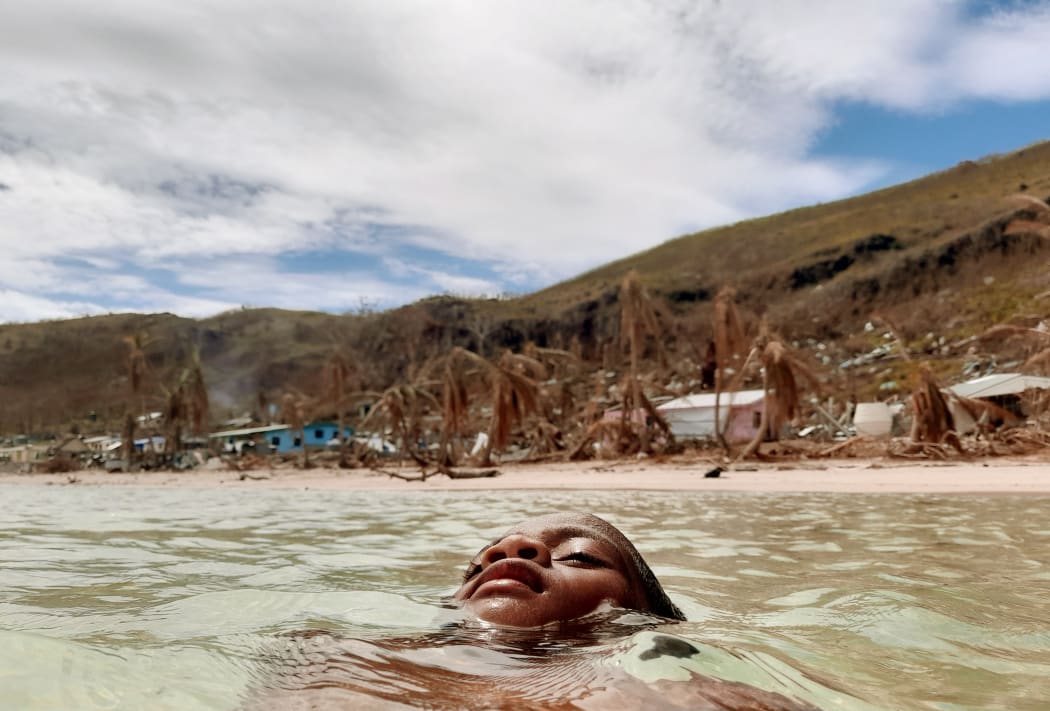 Ten year old Epineri Lata takes a dip in the ocean to escape the intense heat on the island of Kia in Fiji. In the background is the visible evidence of cyclone damage to the island.