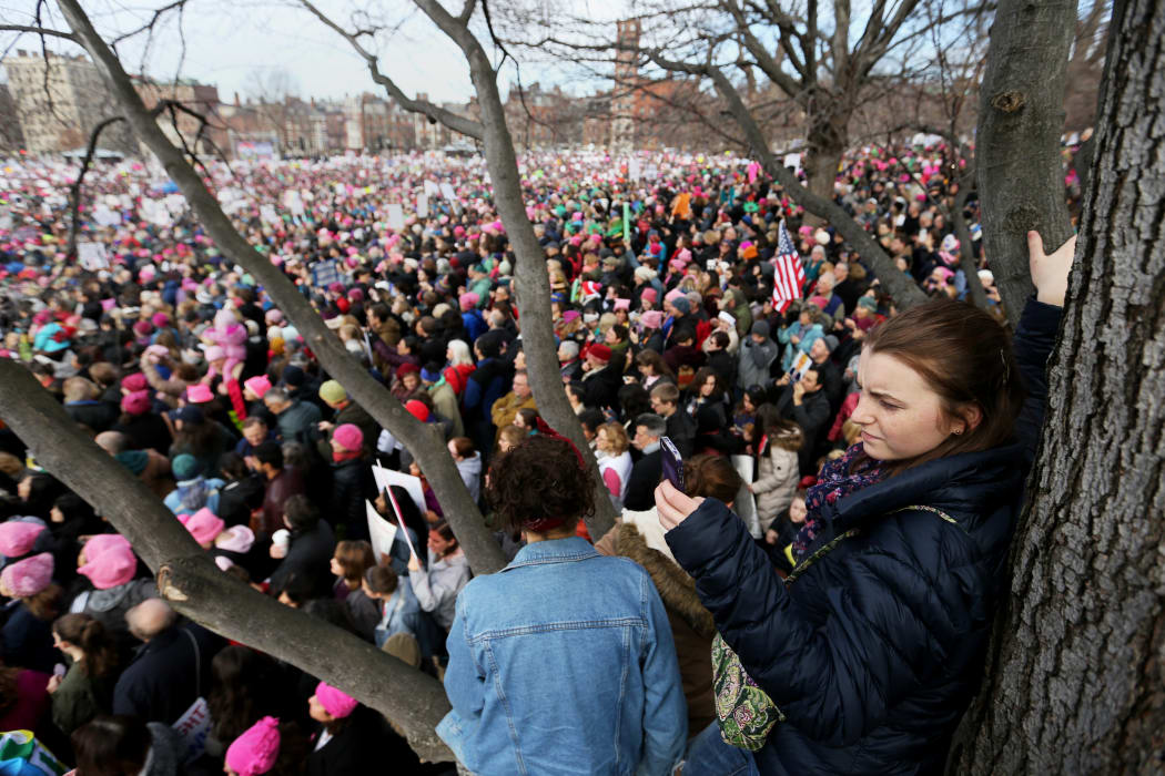 Natalie Krieg of Cambridge takes photos with her phone from a tree in Boston Common during the Boston Women's March for America on January 21, 2017 in Boston, Massachusetts.