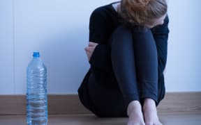 Photo of a sad looking anorexic girl with a bottle of water beside her