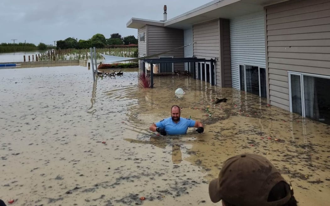 Police using a small boat rescue a resident from a flooded property in Meeanee in Napier