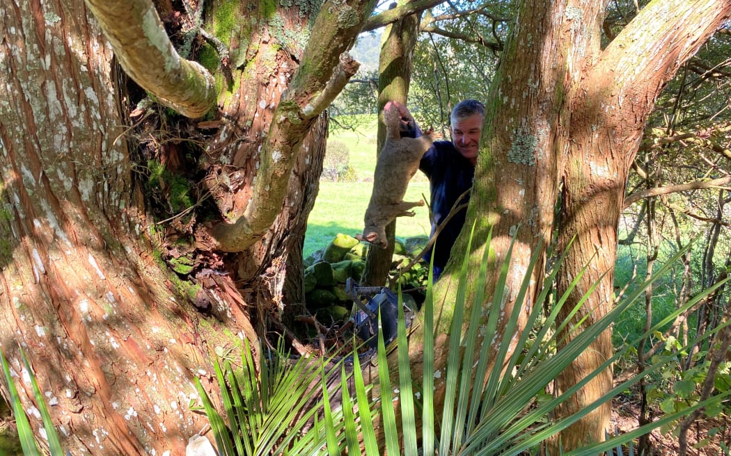 Geoff proudly holds up a dead possum after catching it in a trap.