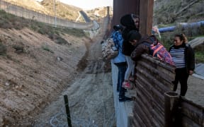 Central American migrants cross the US-Mexico border fence from Tijuana to San Diego County as seen from Tijuana, Baja California State, Mexico, on December 27, 2018.