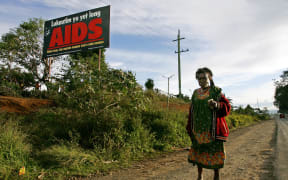 A woman walks past a HIV/AIDS billboard in PNG