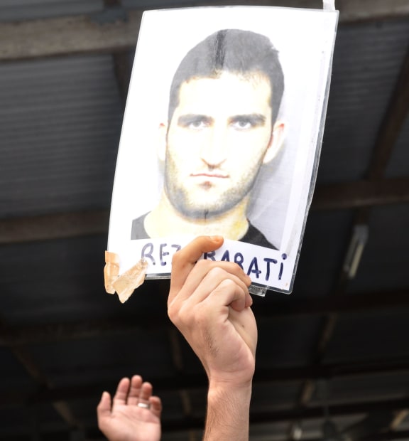 An asylum-seeker holds a picture of Reza Berati who died at the detention centre