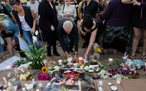 People place candles and flowers next to a photo of British backpacker Grace Millane during the vigil at Civic Square Park in Wellington.