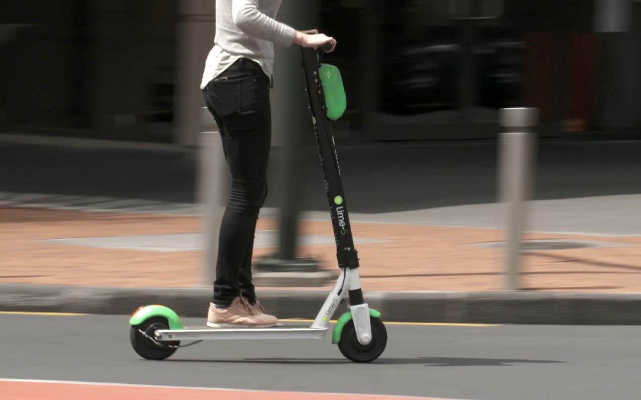 Person riding a Lime scooter in Auckland city.