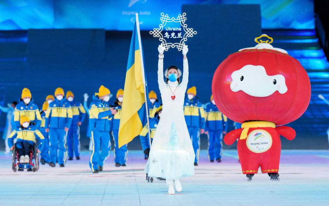 The Ukraine Paralympic team are led out onto the stage alongside Shuey Rhon Rhon, mascot of the Beijing 2022 Paralympic Winter Games.