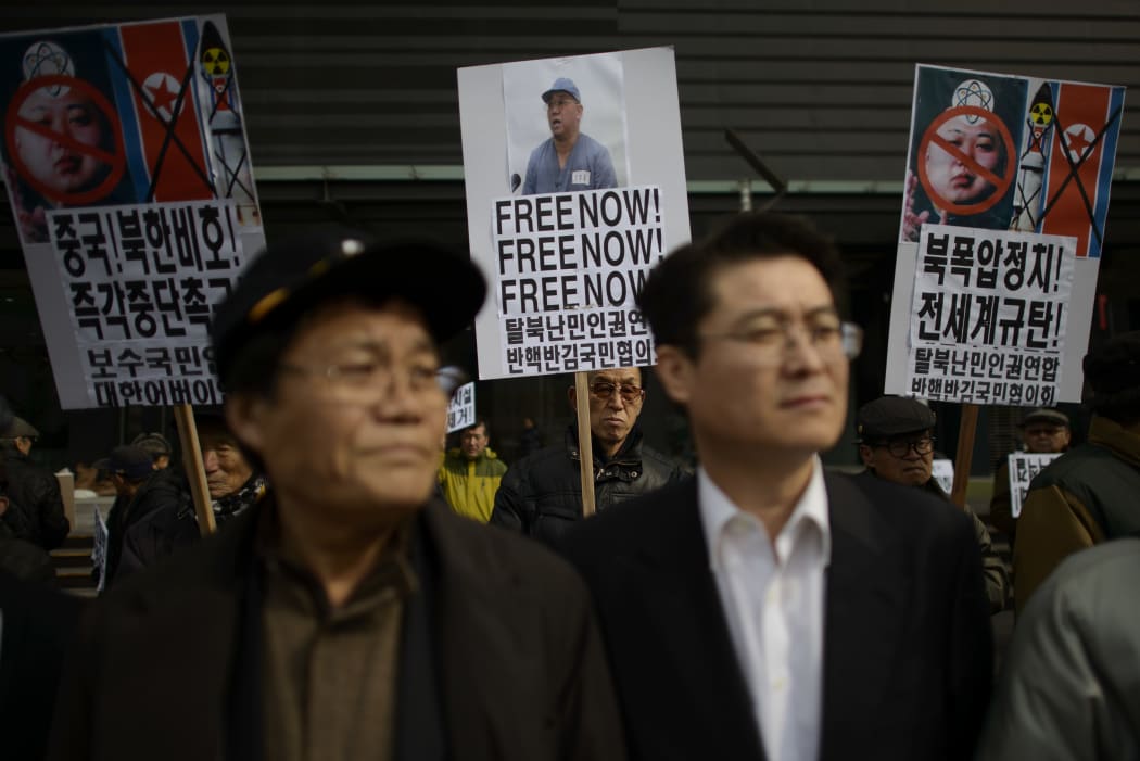 An activist (C) holds a placard calling for the release of Kenneth Bae during a protest against the North Korean regime, in Seoul on 16 Febraury 2014.