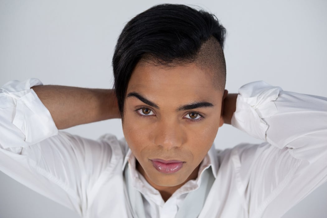 A photo of a young transgender woman in a  stylistic pose with arms behind her head