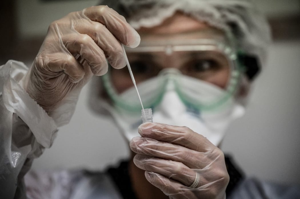 (FILES) In this file photo taken on September 22, 2020 A medical assistant takes a sample from a patient for a coronavirus (Covid-19) test at an analysis laboratory in Le Peage-de-Roussillon, some 30kms south of Lyon, south-eastern France.
