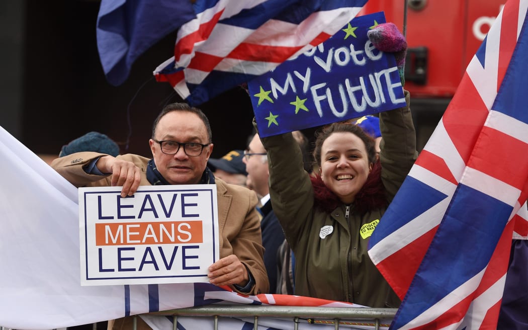 A pro-Brexit protester, left, and a supporter of a second EU referendum hold up their placards outside Parliament as MPs prepare to vote on Prime Minister Theresa May's Brexit deal.