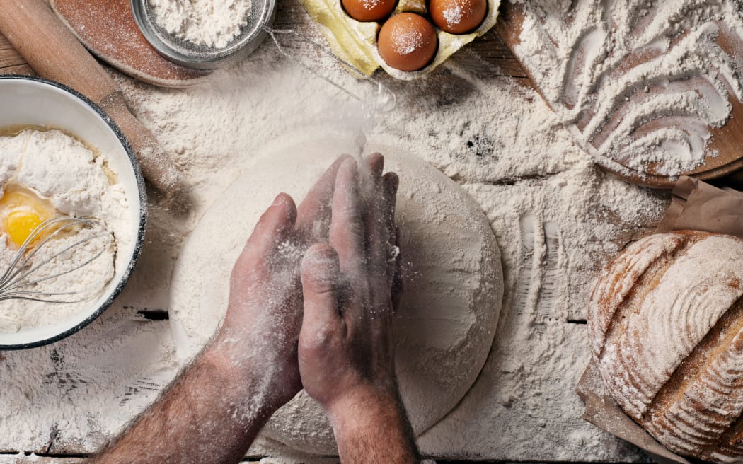 Male baker slaps on dough. Male baker prepares bread. Making bread. Top view. Rustic style