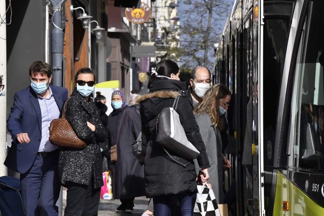 People wearing protective face masks as a measure against the spread of the Covid-19 (novel coronavirus) pandemic, take a tramway on October 22, 2020 in a street of Saint-Etienne, central eastern France.