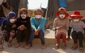 Displaced Syrian girls wear face masks decorated by artists during a COVID-19 awareness campaign at the Bardaqli camp in the town of Dana in Syria's northwestern Idlib province, on April 20, 2020.