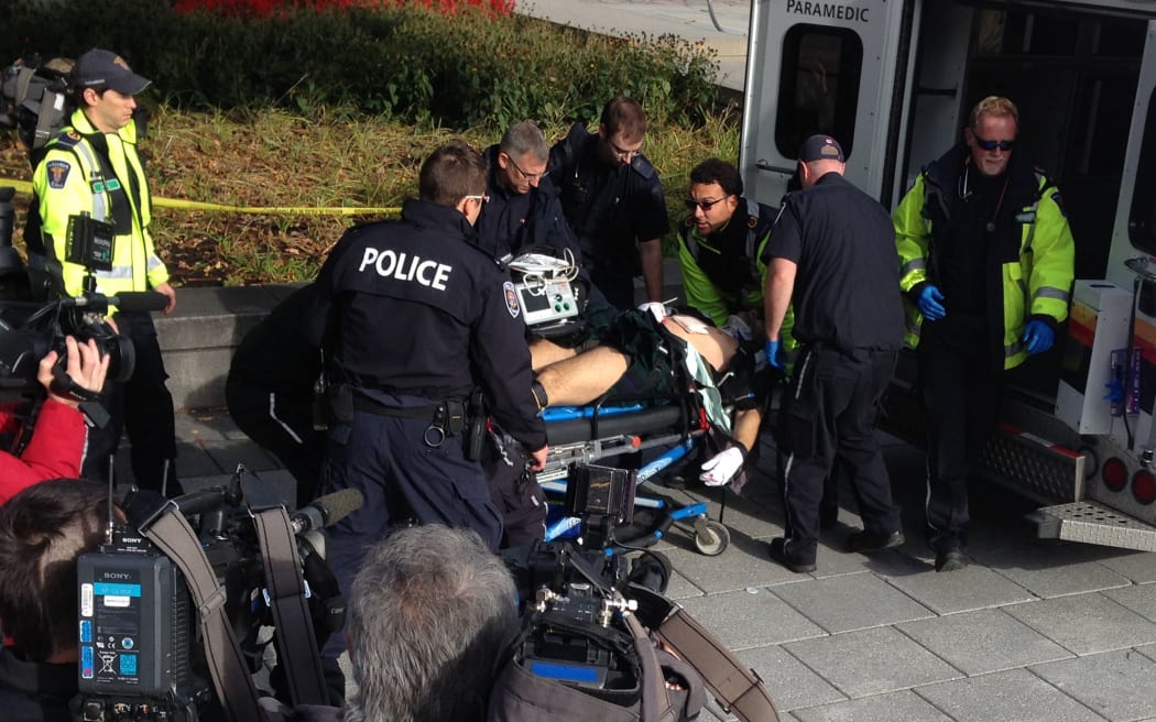 Police and medical personnel moving a wounded Canadian soldier into an ambulance at the scene of a shooting at the National War Memorial in Ottawa.