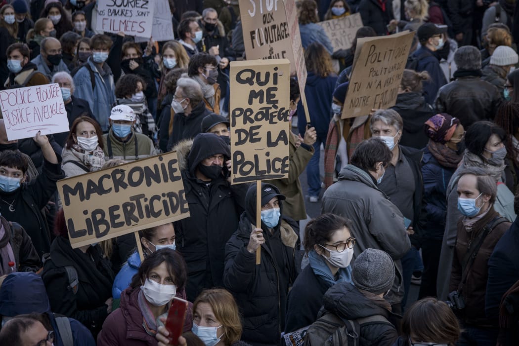 Protesters in Paris hold signs criticising the Global Security Law, and French president Emmanuel Macron.