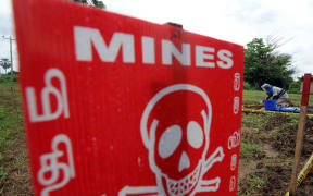 A man de-mines a road behind a warning sign at Sri Lanka,in 2009.