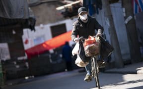 A man rides a bike in a street in Wuhan, Hubei province, 16 February 2020.