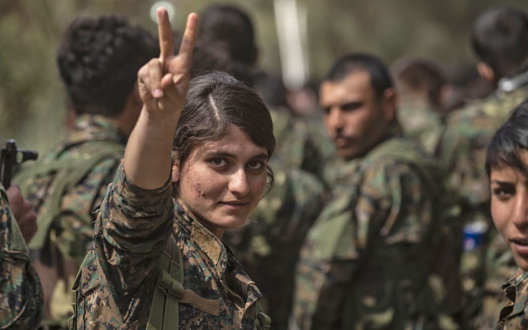 A female fighter of the US-backed Kurdish-led Syrian Democratic Forces (SDF) flashes the victory gesture