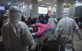 Medical staff wearing protective clothing coronavirus arrive with a patient at  Wuhan Red Cross Hospital.