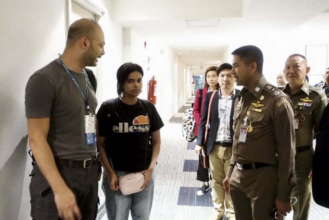 This handout picture January 7, 2019 shows 18-year-old Saudi woman Rahaf Mohammed al-Qanun (2nd L) being escorted by a Thai immigration officer (R) and United Nations High Commissioner for Refugees (UNHCR) officials at Suvarnabhumi international airport in Bangkok.