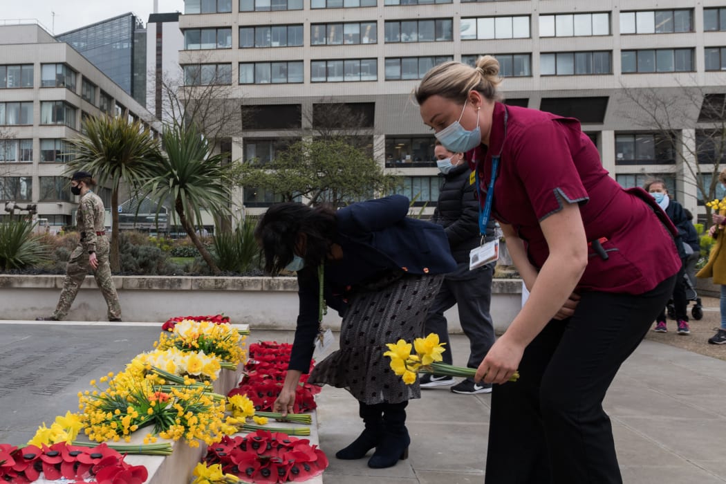 NHS staff lay flowers outside St. Thomas's hospital in central London to remember those who have died from the Coronavirus as part of the National Day of Reflection held one year since lockdown.