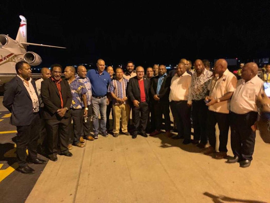 Papua New Guinea prime minister Peter O'Neill (centre, red shirt) surrounded by MPs afer arriving at Port Moresby's Jackson's Airport.