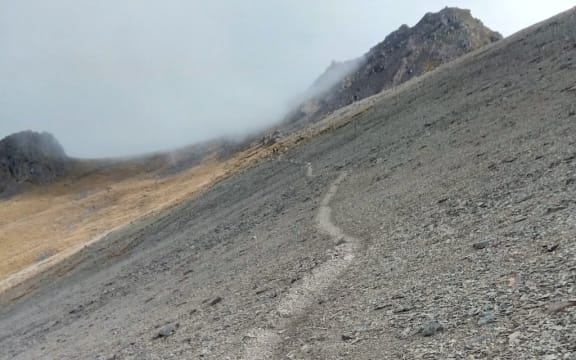 An image of a sheer scree slope with a barely-there trail on the side.