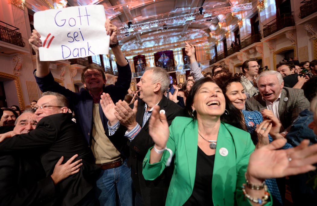 Supporters of Alexander Van der Bellen,one holding a sign reading "Thank God", celebrate as early results come in.