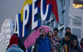 Pedestrians walk past a sign promoting this week's APEC summit in Beijing.