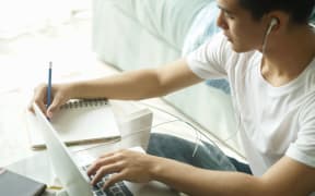 asian young student man teenager entrepreneur wear earphones working with computer studying learning online at home. e-learning webinar meeting. social distance in covid pandemic