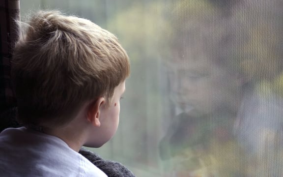 A little boy looking out a window