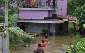 Residents wade through flood waters to their marooned houses
