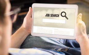 Man trying to find work with online job search engine on tablet.