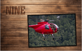 A timber wall reminiscent of a hunting hut has the word "nine" stamped into it like a cattle brand. On the wall is a photo of a red helicopter with a hunter aiming our the door with a rifle