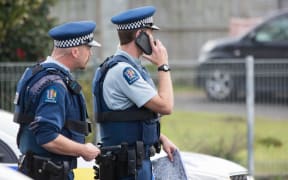 Two police stand in the middle of the street inside a cordon in South Auckland.