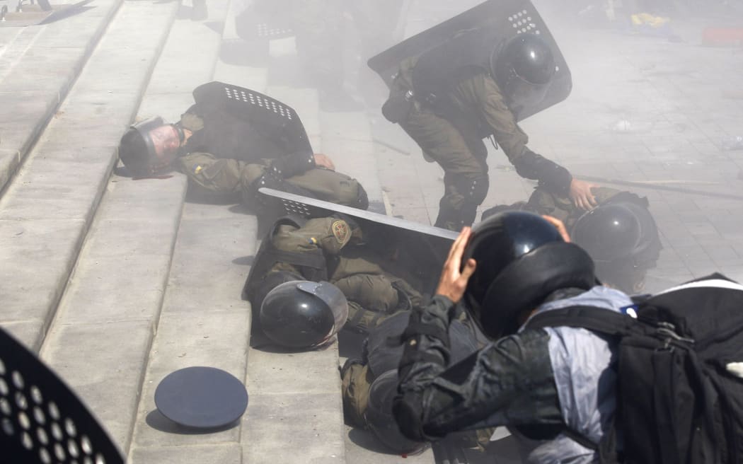 Police help injured comrades after clashes with protesters outside Ukraine's parliament.