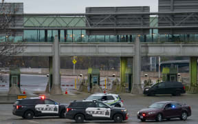 Canadian police cars are seen near the Rainbow Bridge border crossing into the US in Niagara Falls, Ontario, after a car exploded at a US-Canada checkpoint on November 22, 2023. US terrorism investigators deployed Wednesday after a car erupted into a fireball at a US-Canada checkpoint, triggering border closures on one of the busiest travel days in the American holiday calendar. Two people were killed in the blast, according to US media citing authorities, although their identities were not yet public. (Photo by Peter Power / AFP)